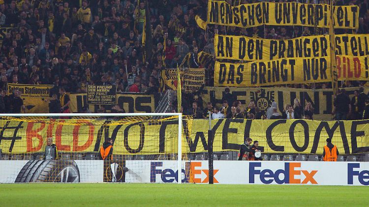 Die Fans von Borussia Dortmund protestieren beim Spiel gegen FK Krasnodar gegen die größte deutsche Tageszeitung. Ihr Verein macht bei der Flüchtlingsaktion dennoch mit.