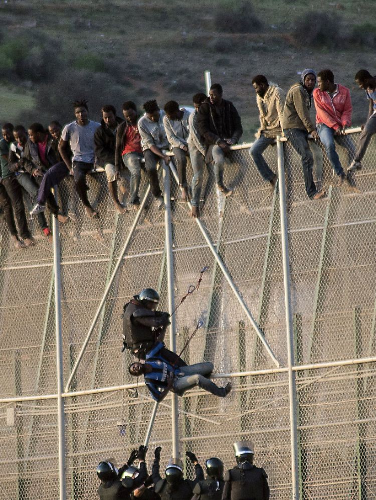 Ein spanischer Grenzsoldat holt einen Afrikaner vom Zaun, der Melilla von Marokko trennt.