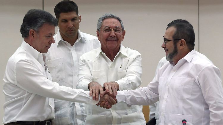 Der kubanische Präsident Raul Castro (M.) hält die Hände des kolumbianischen Präsidenten Juan Manuel Santos (l.) des Farc-Führers Rodrigo Londono "Timochenko" Echeverri.