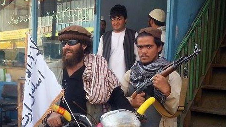 Taliban-Kämpfer (mit der weißen Flagge) durchsuchen Kundus nach Armeeangehörigen und feindlichen Milizionären.
