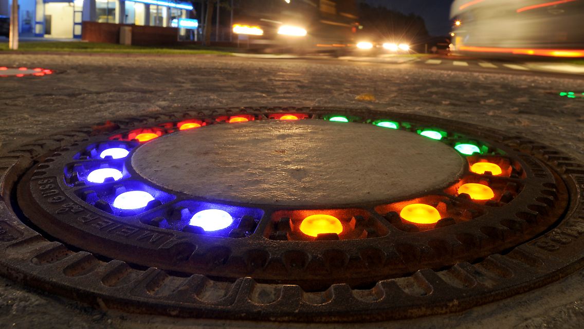 ... fünf Gullydeckel inmitten eines überfahrbaren Kreisverkehrs mit bunten LED-Lichtern zu versehen. Wer nun von Süden in die Gemeinde im Landkreis Osnabrück fährt, wird farbenfroh empfangen.