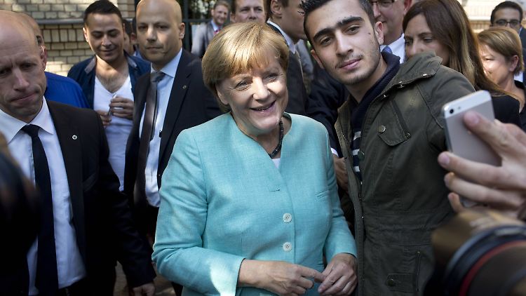 Merkel gewährt einem Flüchtling ein Selfie.