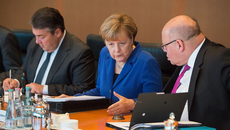 Altmaier und Merkel unterhalten sich zu Beginn der Sitzung des Bundeskabinetts. Wirtschaftsminister Gabriel sitzt daneben.