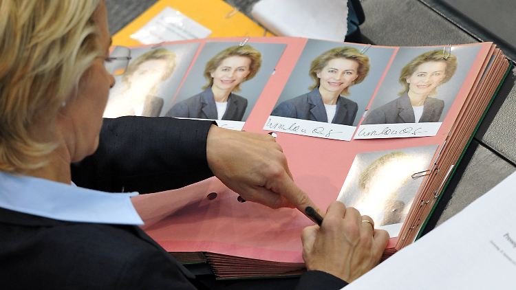Von der Leyen nutzt die  Bundestagsdebatte, um ihre Autogrammkarten zu signieren. 