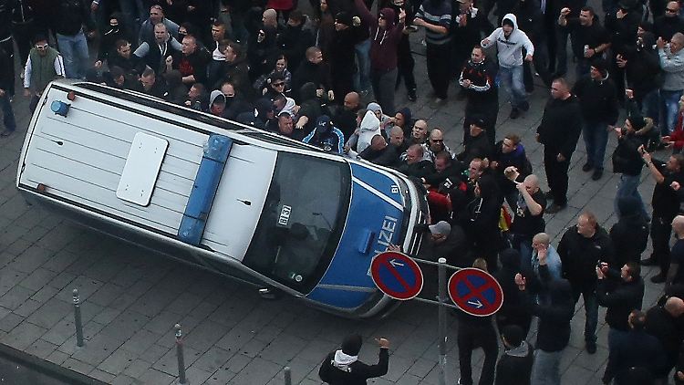 Bei der "Hogesa"-Demo kippen Demonstranten ein Polizeiauto um. 50 Polizisten werden bei den Ausschreitungen 2014 in Köln verletzt. 