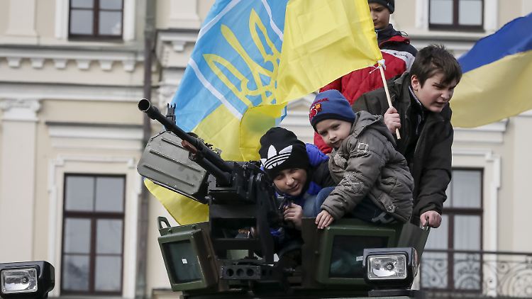 Ukrainische Kinder spielen in Kiew auf einem Panzer.