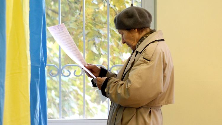 Eine Frau studiert in Kiew ihren Stimmzettel.
