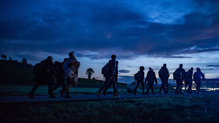 Flüchtlinge gehen an der deutsch-österreichischen Grenze in die Dunkelheit.