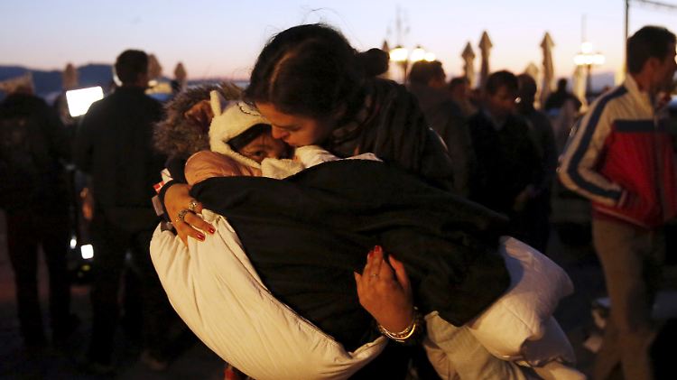 Eine Helferin hält ein gerettetes Kind im Arm, nachdem ein Flüchtlingsboot vor der Insel Lesbos gesunken ist.