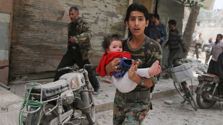 Alltag in Aleppo: Ein junger Mann bringt ein Kind nach dem Einschlag einer Fassbombe in Sicherheit.