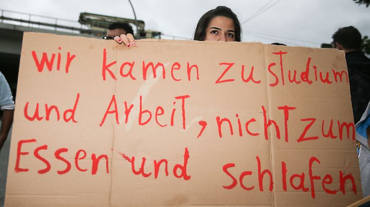 Eine Frau hält ein Plakat vor einer Hamburger Flüchtlingsunterkunft in die Höhe. Zu welchen Bedingungen Flüchtlinge arbeiten können, ist derzeit Gegenstand der Debatte.