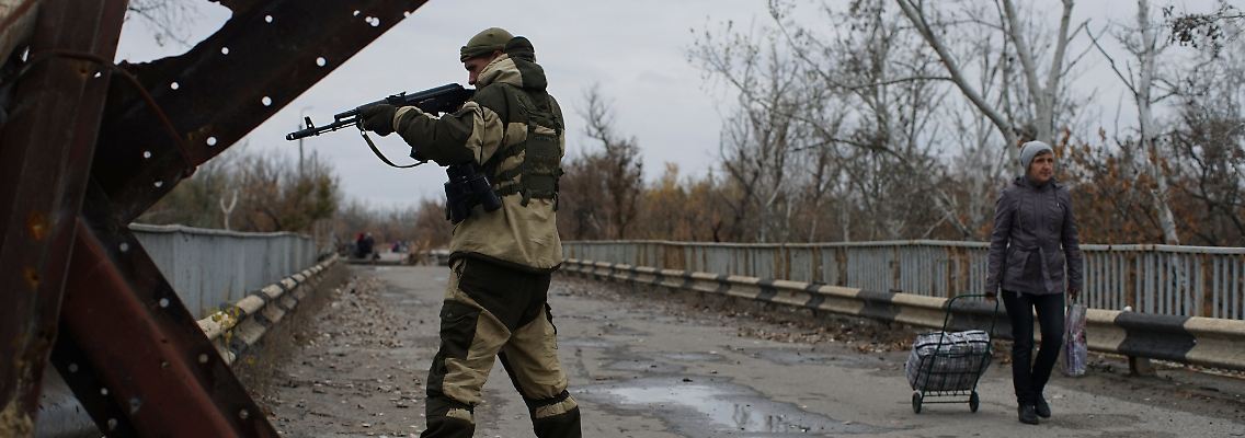 Ein Anhänger der russischen Separatisten bewacht eine wiederaufgebaute Brücke in der Ostukraine.