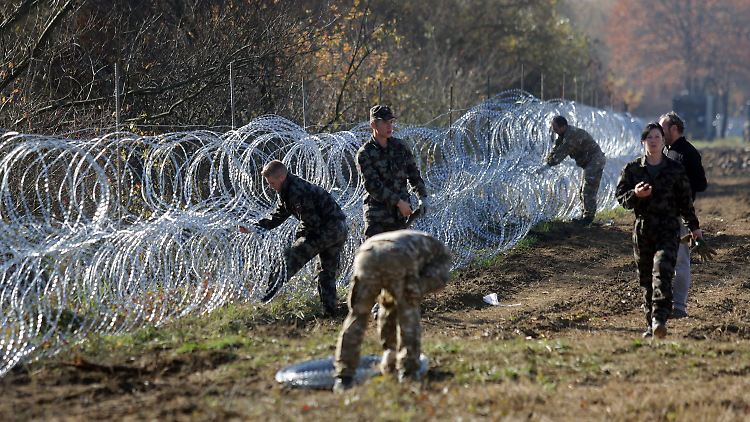 Slownische Soldaten errichten an der Grenze zu Kroatien eine Stacheldrahtbarriere.