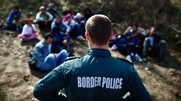 Ein bulgarischer Polizist bewacht eine Gruppe syrischer Flüchtlinge an der Grenze zur Türkei.