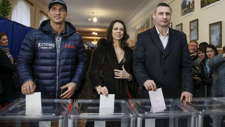 Vitali Klitschko (r.) zusammen mit seiner Frau Natalia und seinem Bruder Wladimir bei der Stimmabgabe.