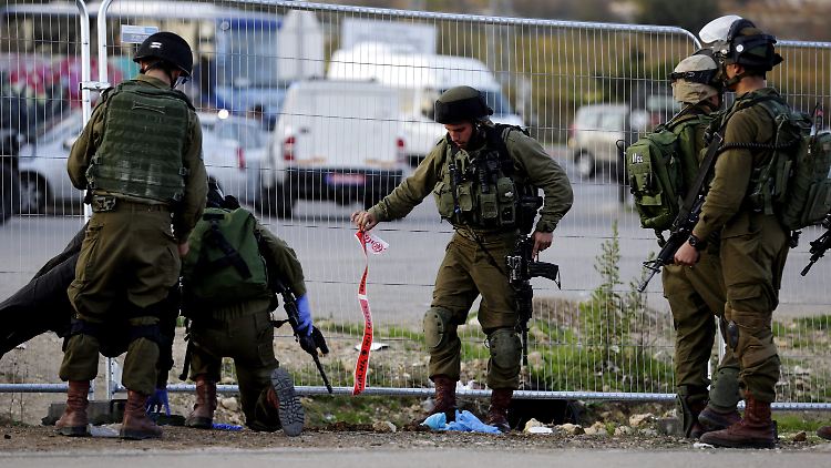 Israelische Soldat untersuchen den Tatort nachdem es an einer Bushaltestelle zu einer Attacke durch Palästinenser kam.