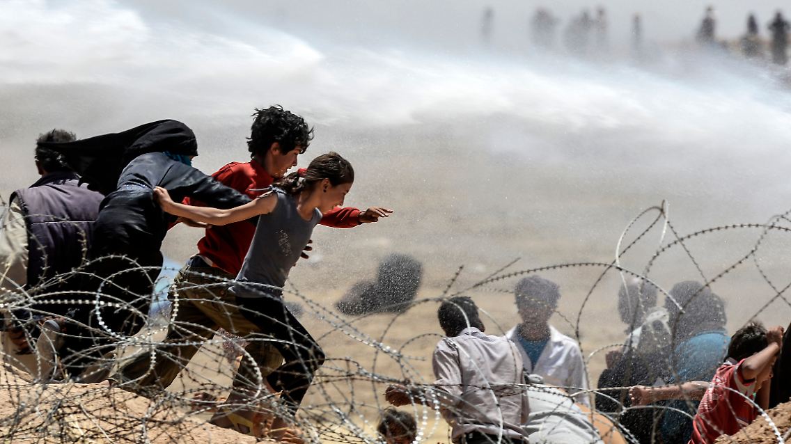 Kinder fliehen im Juni durch den Stacheldraht an der türkisch-syrischen Grenze vor den Gefechten kurdischer Kämpfer und dem IS. Der türkische Fotograf Bülent Kilic hat diese Tragödie für die französische Nachrichtenagentur AFP festgehalten.