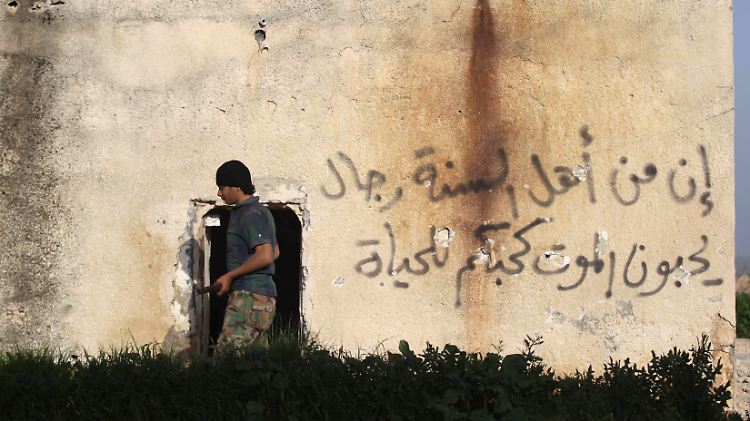 Aufständischer in Syrien. An der Wand steht: "Unter den sunnitischen Männer gibt es einige, die den Tod lieben wie du das Leben."