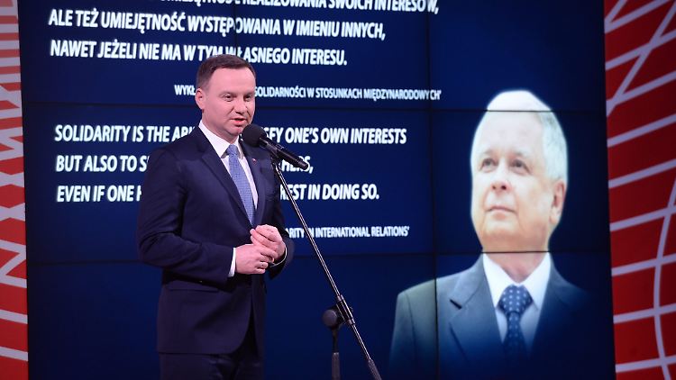 Der Präsident und der Mann im Hintergrund: Präsident Andrzej Duda vor einem Plakat mit Jaroslaw Kaczynski.