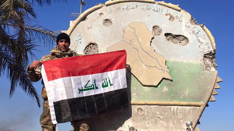 Ein irakischer Soldat steht mit der Flagge des Landes auf dem Regierungsgebäude in Ramadi.