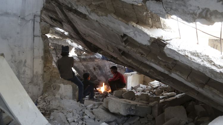 In der Ruine eines zerstörten Gebäudes im syrischen Maaret al-Numan wärmen sich Jungs am Feuer.