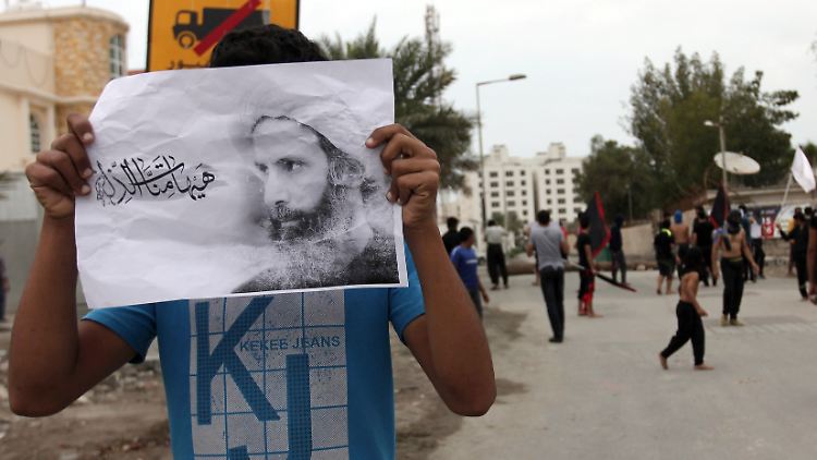 Ein Demonstrant hält ein Bild von Nimr al-Nimr in den Händen.