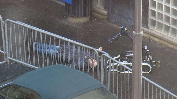 Der Erschossene wird von einem Sprengstoffroboter untersucht.
