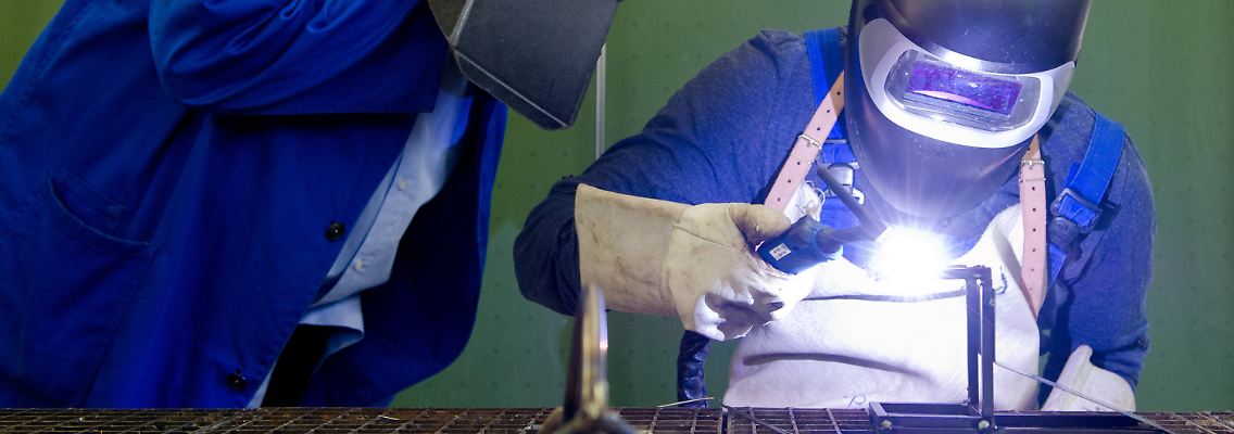 Ein Auszubildender setzt eine Schweißnaht - unter den kritischen Augen des Berufsschullehrers.