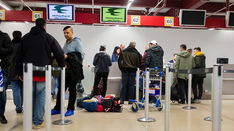 Reisende und Flüchtlinge stehen im Flughafen Tegel am Check-In-Schalter für einen Flug nach Erbil.