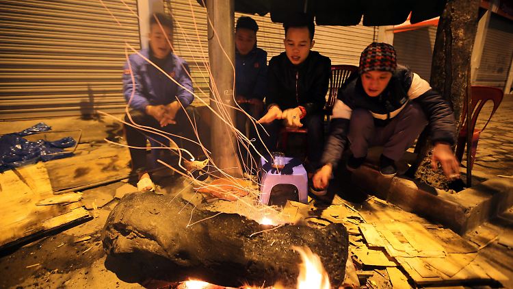 Diese Vietnamesen schützen sich am offenen Feuer vor den ungewohnten Temperaturen.
