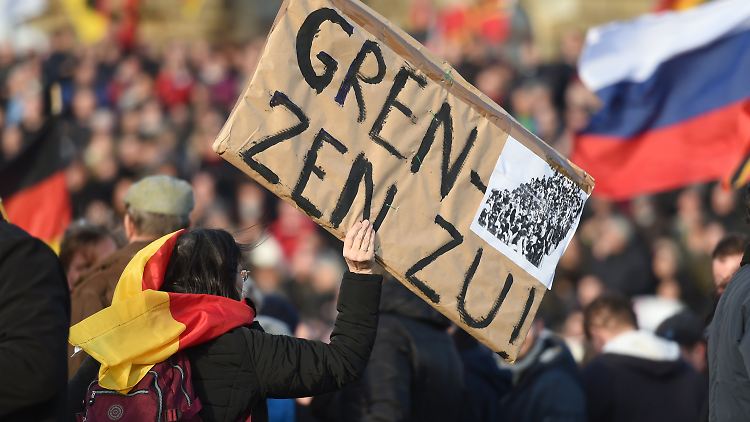 Eine Teilnehmerin einer Pegida-Kundgebung macht ihre Meinung auf einem Plakat deutlich.