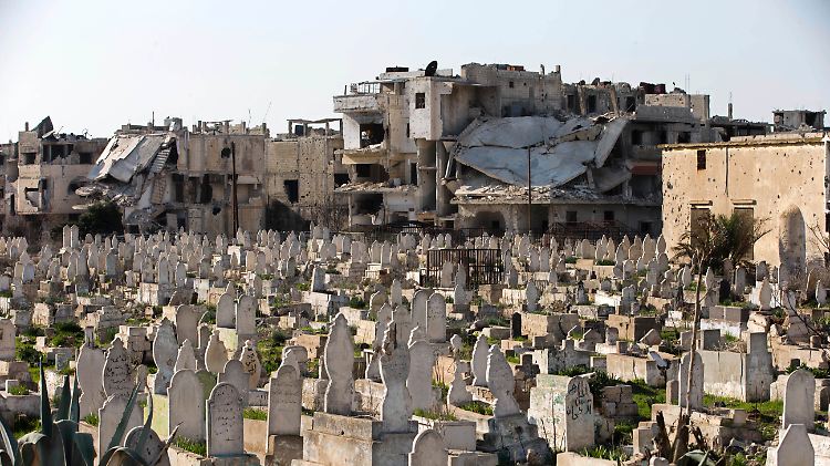 Ein Friedhof in der syrischen Stadt Homs - vor zerstörten Häusern.