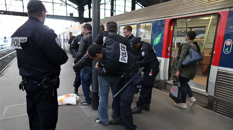 Französische Polizisten filzen einen Mann an einem Pariser Bahnhof.