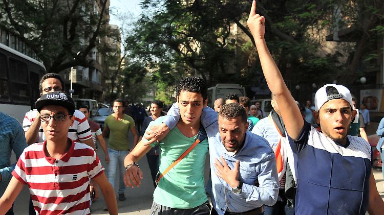 Ein Mann in Kairo hilft einem Mitdemonstranten - er war Tränengas ausgesetzt.