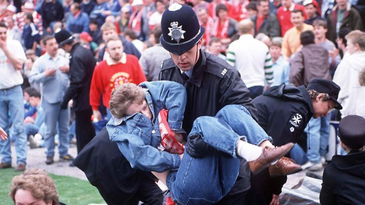 Ein Polizist trägt einen Liverpool-Fan in den Innenraum des Hillsborough-Stadions. Für 96 Fans aus dem überfüllten Block aber kam jede Hilfe zu spät.