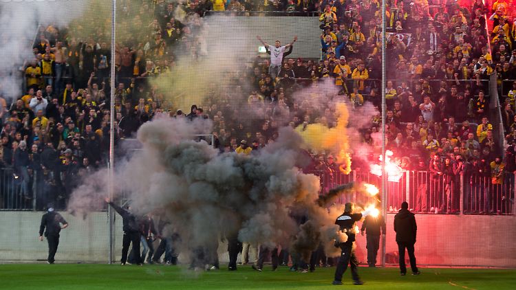 Aufstiegsfeier à la Dynamo Dresden: Im Stadion des künftigen Zweitligisten rennen Vermummte auf den leeren Rasen und zünden Rauchbomben.