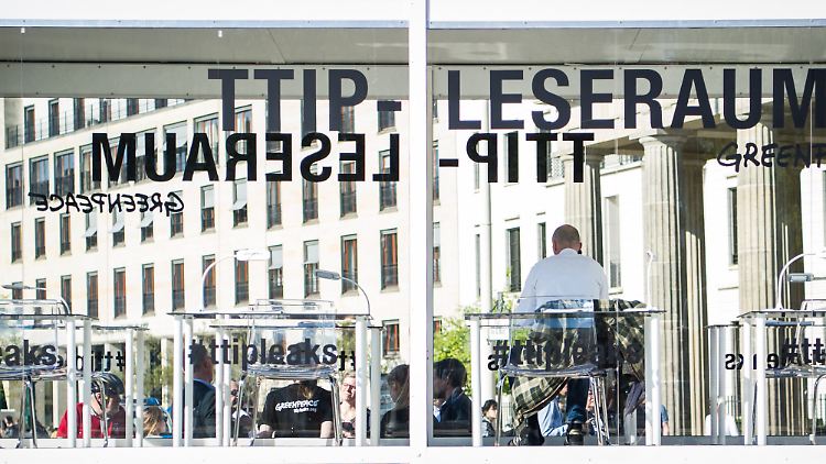 Ein Mann sitzt in einem gläsernen Leseraum vor dem Brandenburger Tor in Berlin und blättert durch die von Greenpeace veröffentlichten TTIP-Dokumente.