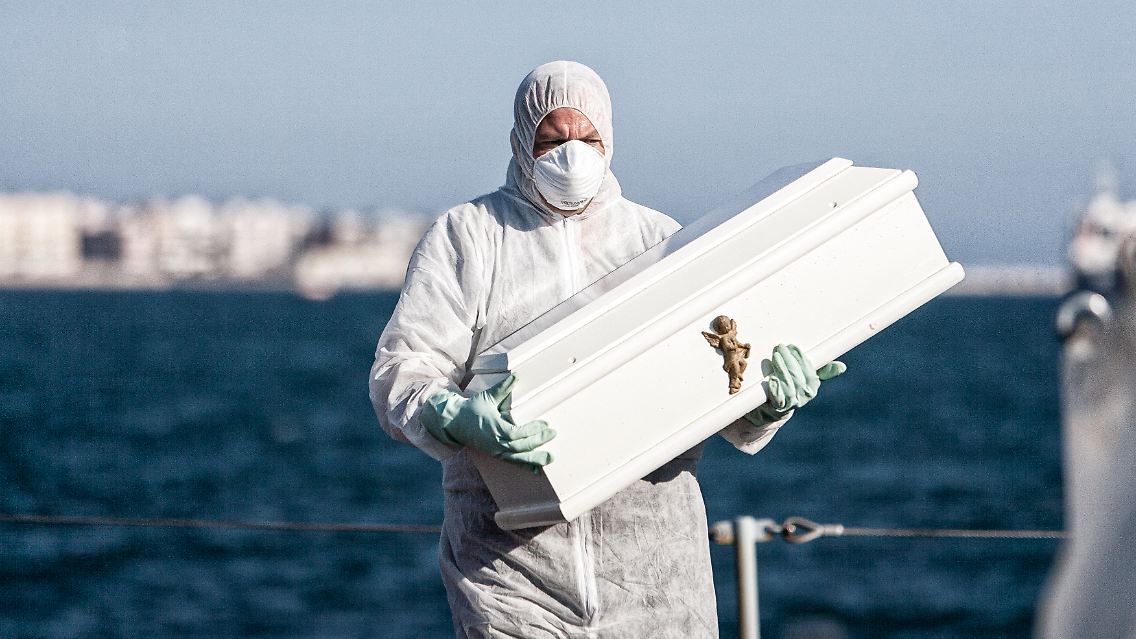 Ein Helfer bringt einen Sarg von Bord eines italienischen Marineschiffs.