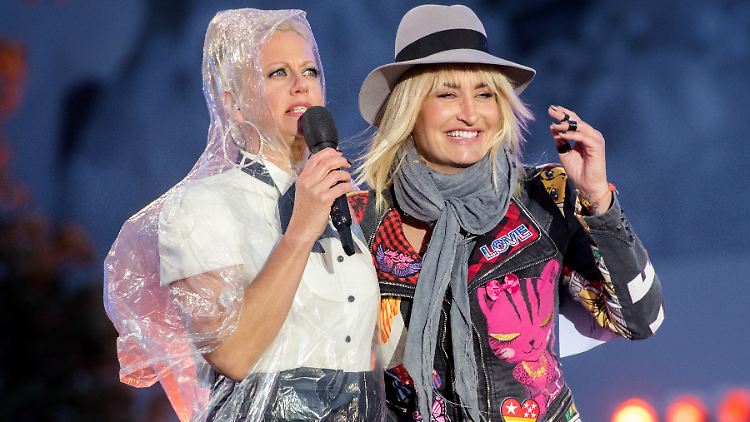 Bei der Grand-Prix-Party hält ein Plastik-Cape Barbara Schöneberger (l.) trocken. Sarah Connor setzt auf Hut.