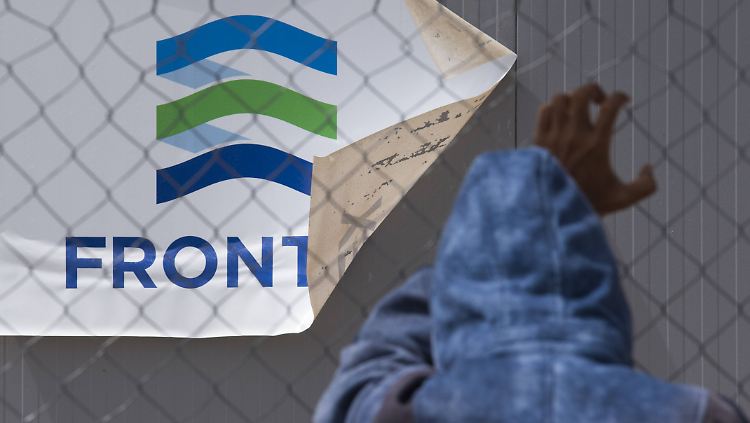 Ein Flüchtling steht auf Lesbos vor einem Schild der EU-Grenzschutzagentur Frontex.