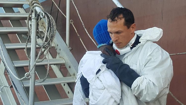 Ein Mitarbeiter der Küstenwache bringt das Baby an Land.
