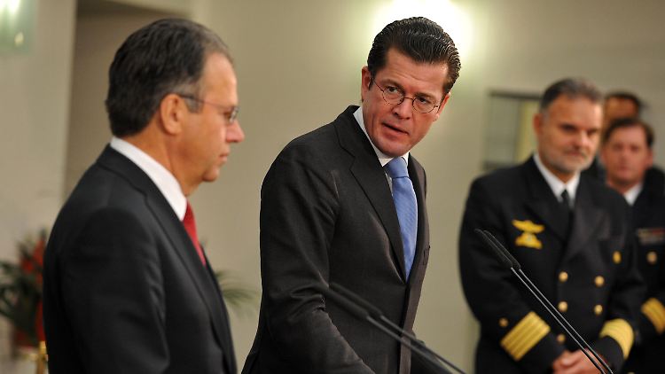 Weise (l.) übergibt Guttenberg (M.) den Bericht.