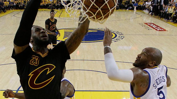 LeBron James (l) kommt an Marreese Speights von den Golden State Warriors vorbei und punktet.