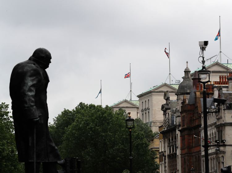 Die Statue von Winston Churchill in London. Der Blick in Richtung öffentlicher Gebäude, auf denen die Flaggen auf Halbmast wehen.