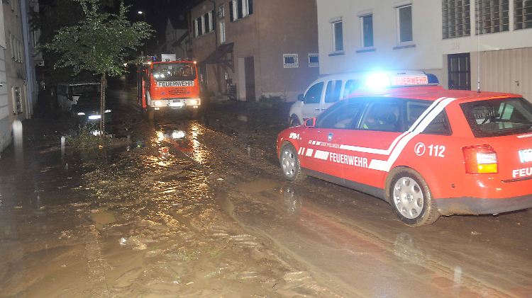 Feuerwehrkräfte versuchen nach einem Starkregen in Pfullingen (Baden-Württemberg) eine überschwemmte und verschlammte Straße zu reinigen.