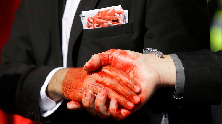 Demonstranten, die sich als Tony Blair und George W. Bush verkleidet haben, reichen sich vor dem Konferenzgebäude, in dem der Chilcot-Bericht vorgestellt wird, die Hände.