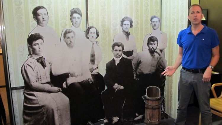 Kibbuz-Vorsteher Schai Schoschani steht vor einem Bild der Gründer des Kibbuz in Degania Alef.