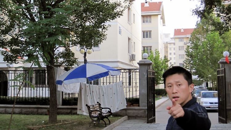 Ein Sicherheitsbeamter weist Journalisten vor dem abgeriegelten Haus von Liu Xia an, keine Fotos zu machen und zu verschwinden.
