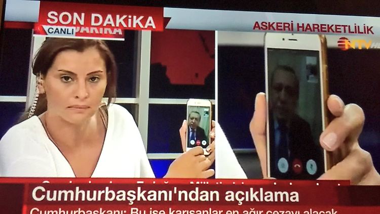 Eine Journalistin vom Sender CNN-Türk hält ein Handy in die Kamera. Zu sehen ist darauf Staatspräsident Erdogan.