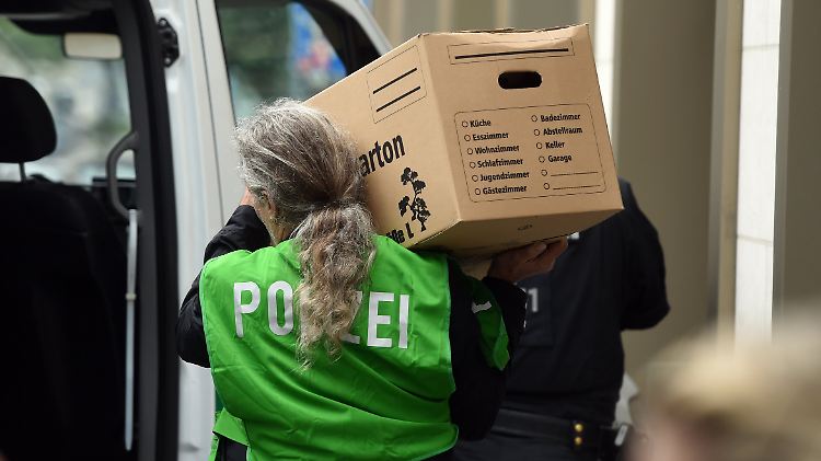 Die Ermittler tragen Kisten voller Beweismaterial aus einer Wohnung.